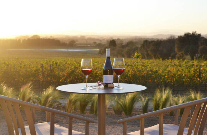 Terraza con mesa preparada para degustar dos copas de vino y vistas al campo anocheciendo