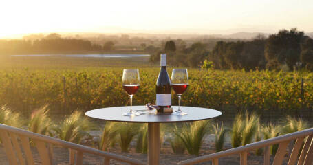 Terraza con mesa preparada para degustar dos copas de vino y vistas al campo anocheciendo