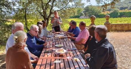 Imagen de una mesa con visitantes en el exterior de la bodega.