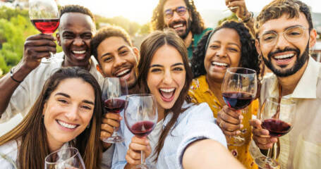 Bild von lächelnden Menschen mit einem Glas Wein in der Hand.