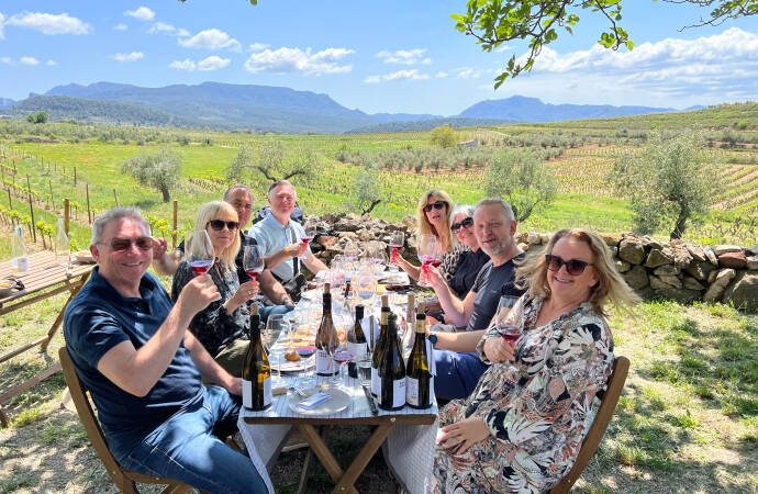 Foto einer Gruppe von Menschen, die in den Weinbergen des Weinguts Wein verkosten.